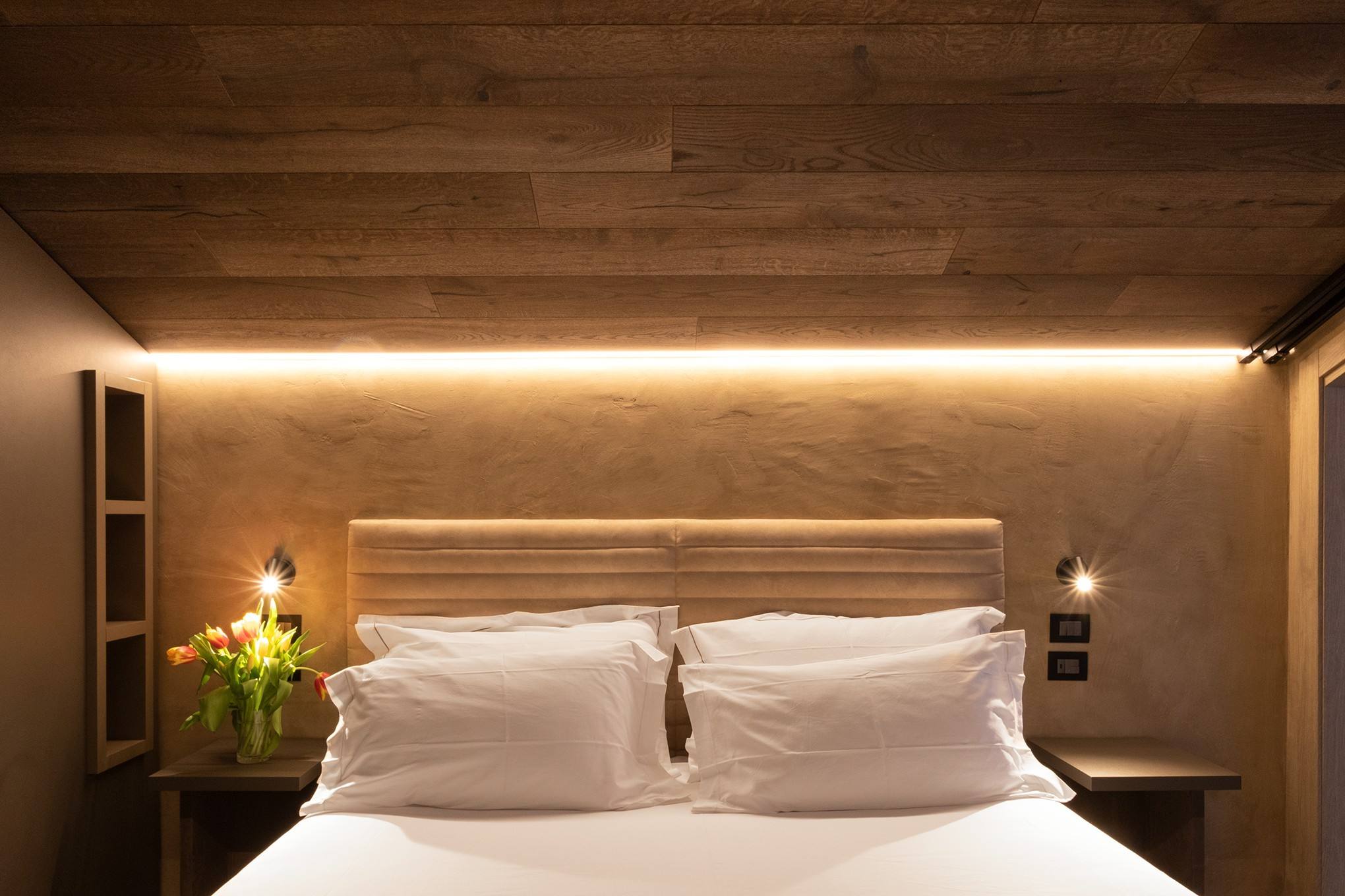 Letto con testiera in legno e luce calda