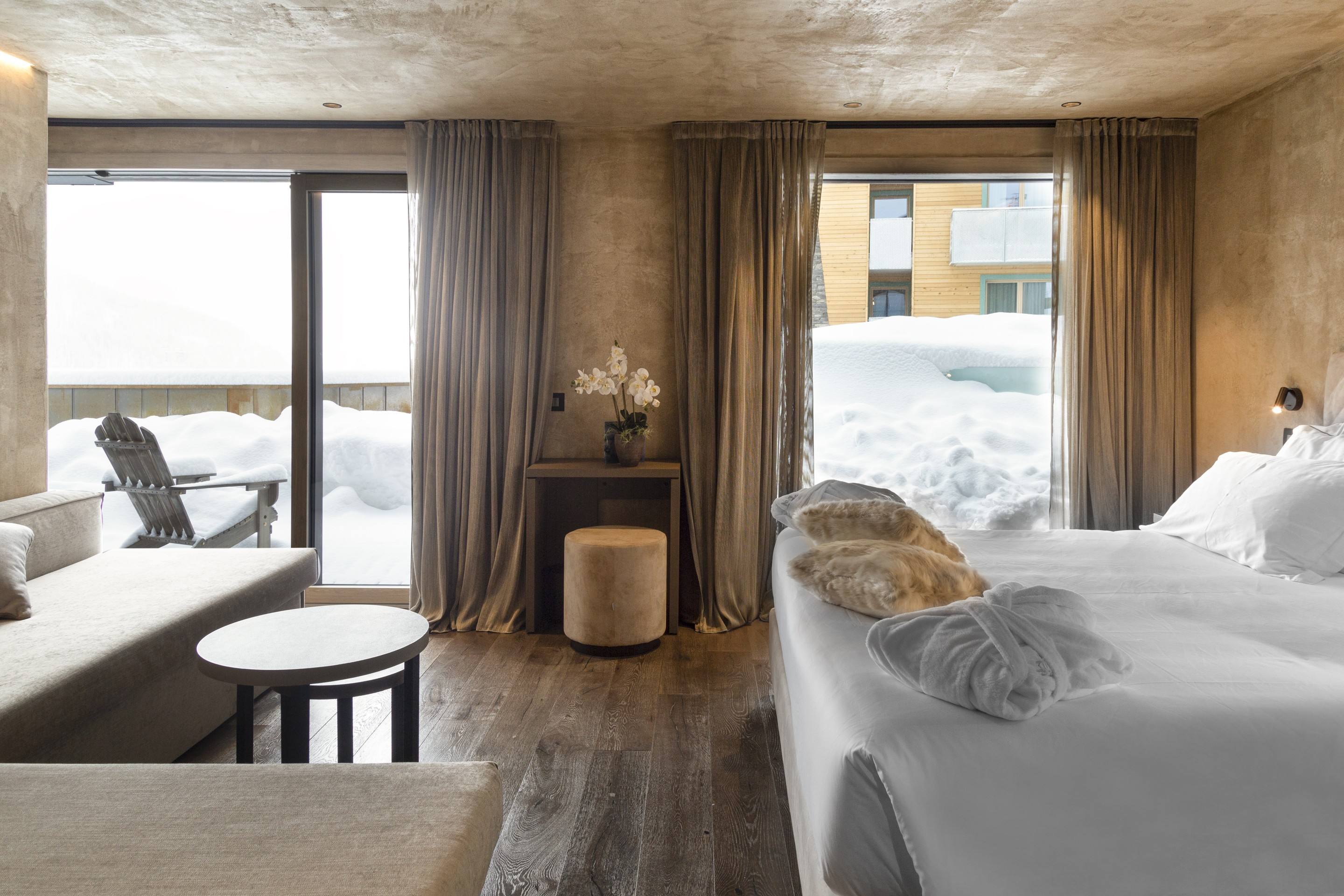 Camera con vetrate sulla neve e letto con accappatoi