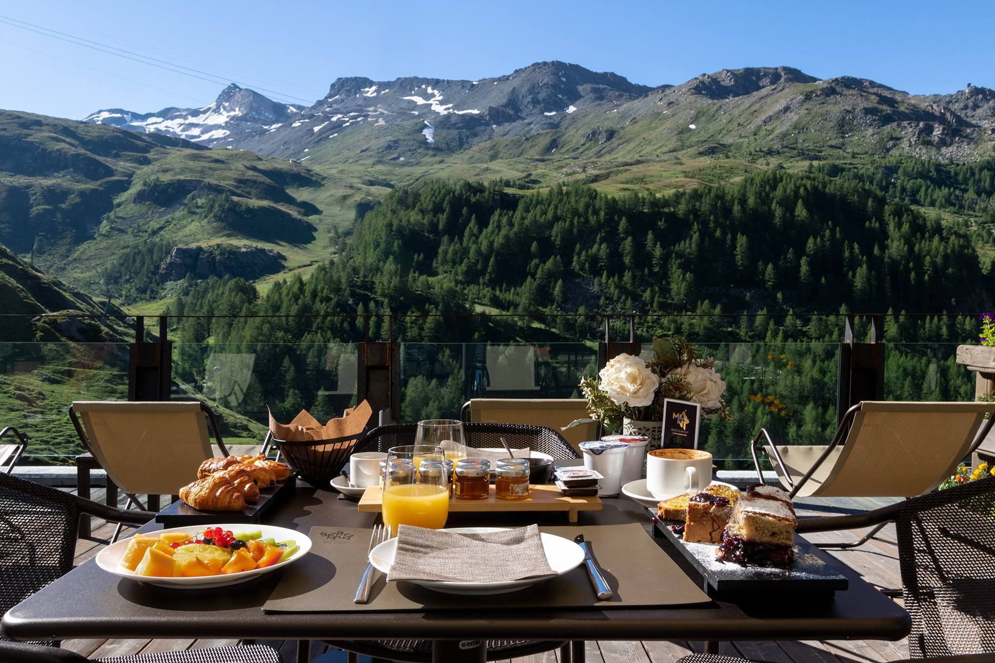 Colazione servita in terrazza d’estate, con boschi e montagne sullo sfondo