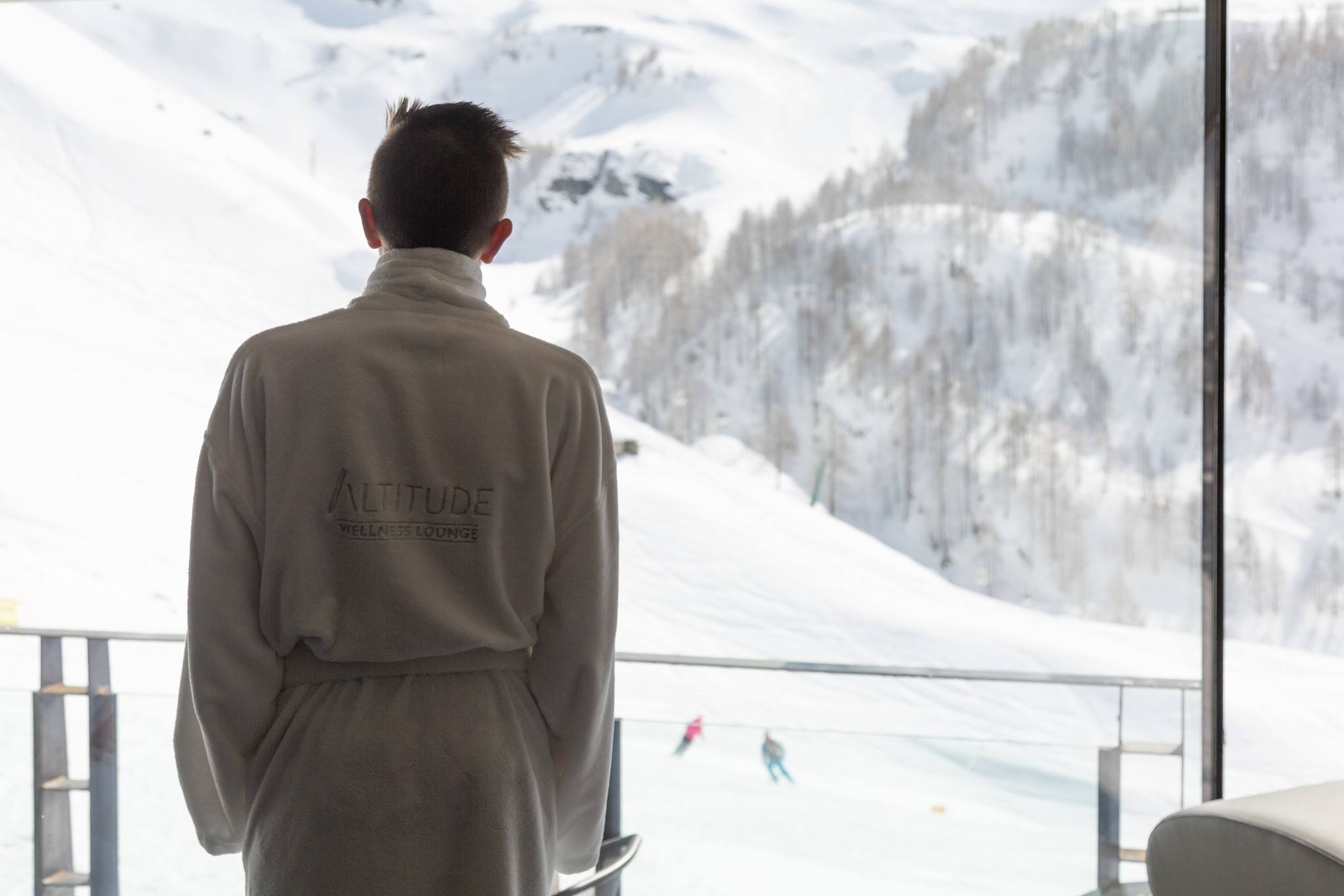 Ospite in accappatoio davanti alla vetrata con vista sulle piste innevate