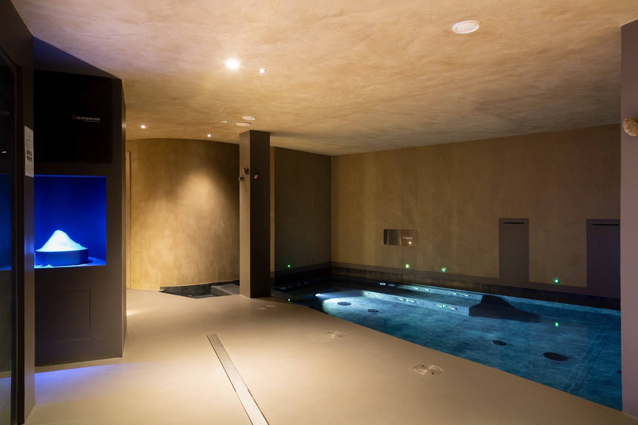 Piscina interna con luce blu e cascata di ghiaccio sullo sfondo