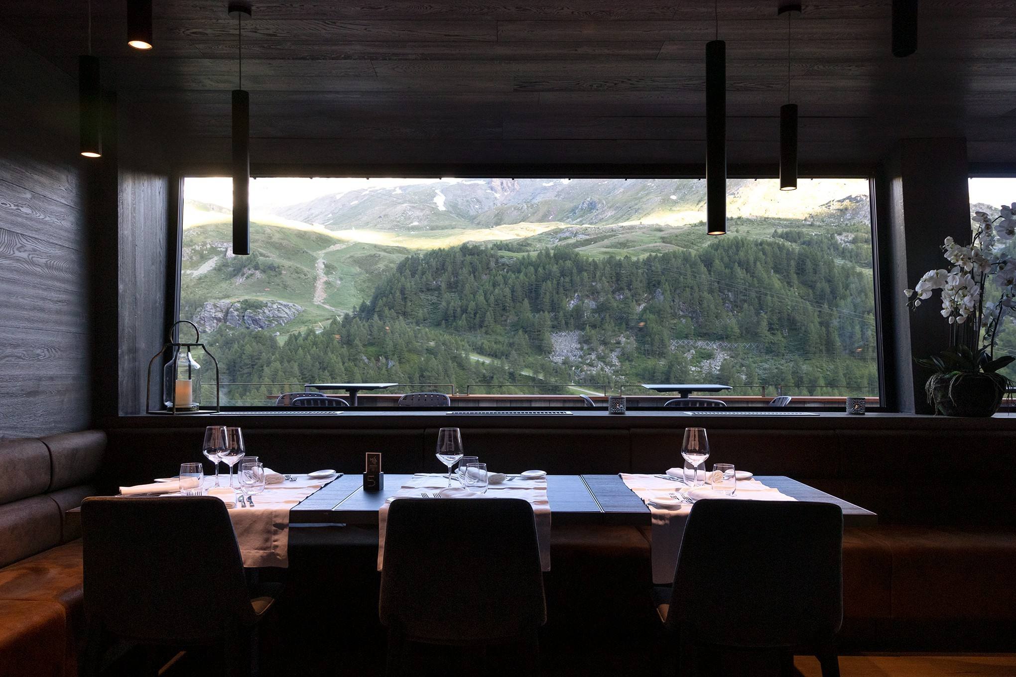 Sala del ristorante con tavoli apparecchiati e vetrata sulla valle