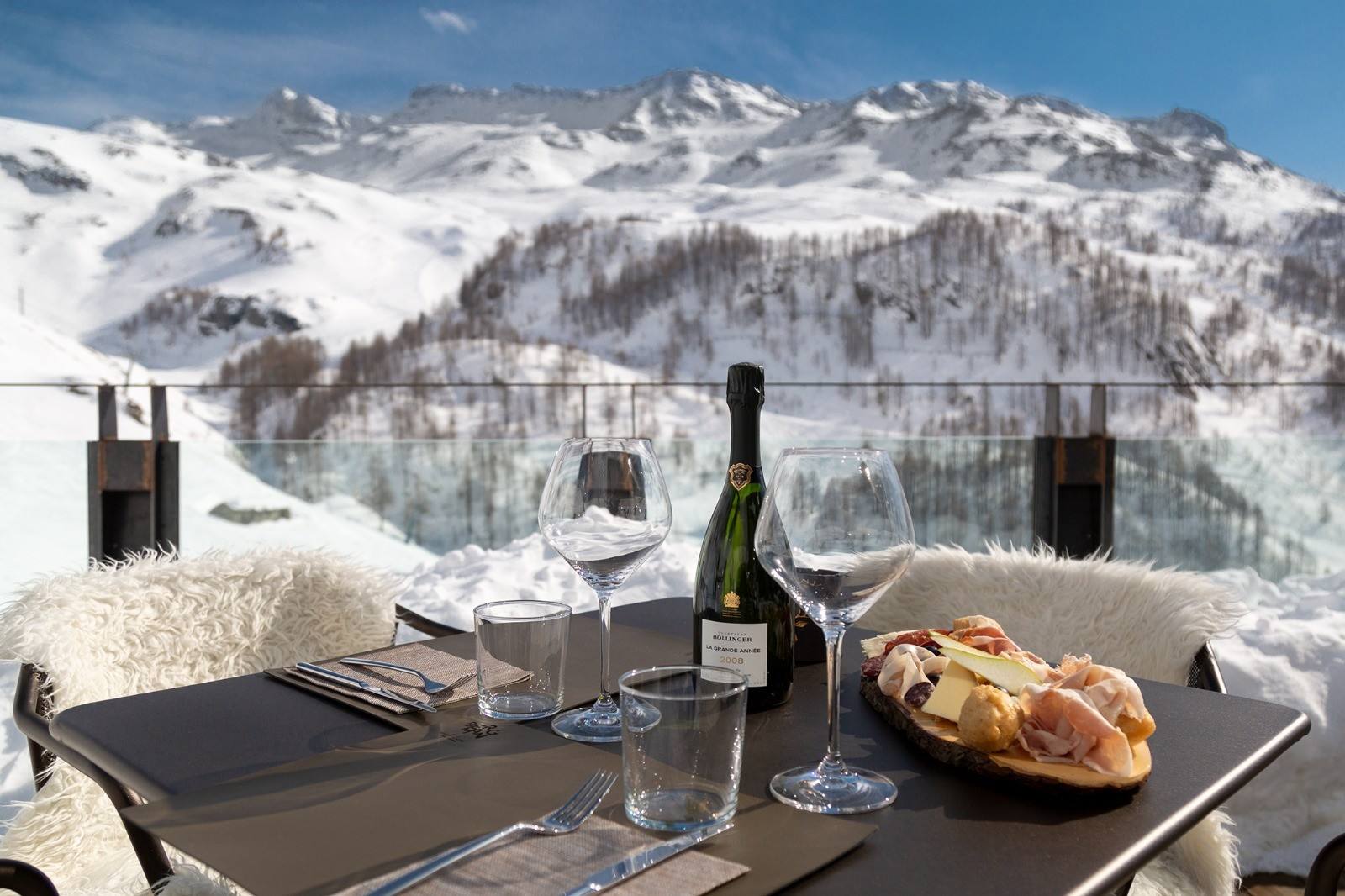 Aperitivo con bollicine e tagliere sulla terrazza innevata, con vista sulle cime